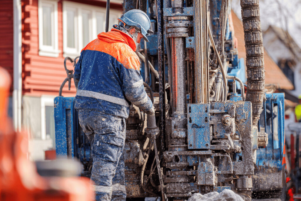Tekniker arbetar vid en bergvärmeborrigg utanför ett svenskt hus under borrningen.