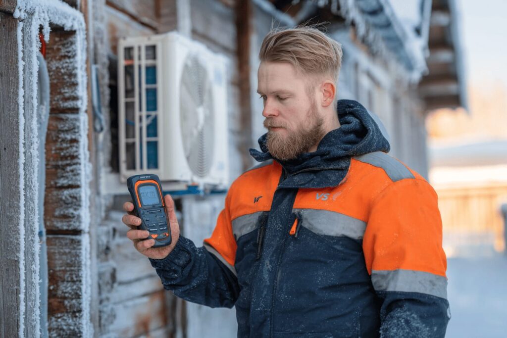 VVS-tekniker som gör en prestandamätning av en värmepump i vinterkyla, med handinstrument för att kontrollera COP- och SCOP-värden samt energieffektivitet i svenska klimatförhållanden.